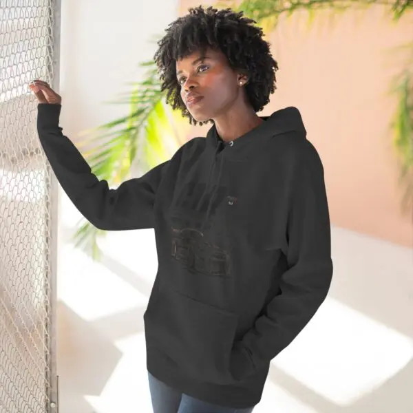 Woman in hoodie leaning on chain-link fence.