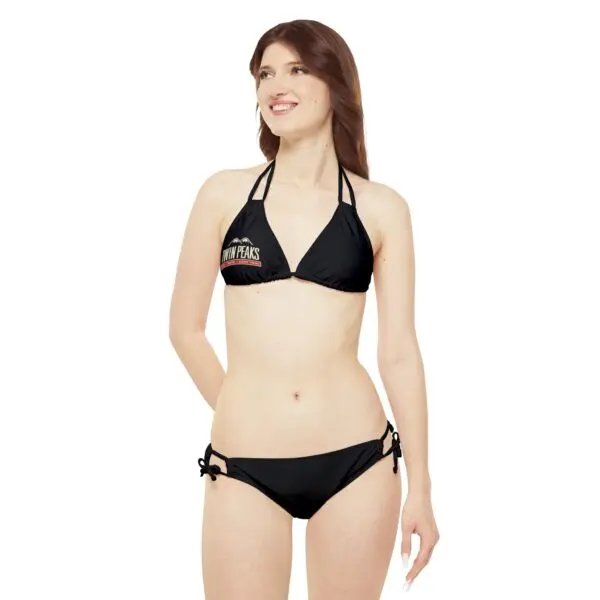Woman wearing a black bikini, smiling.