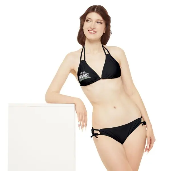 Woman in black bikini smiling confidently.