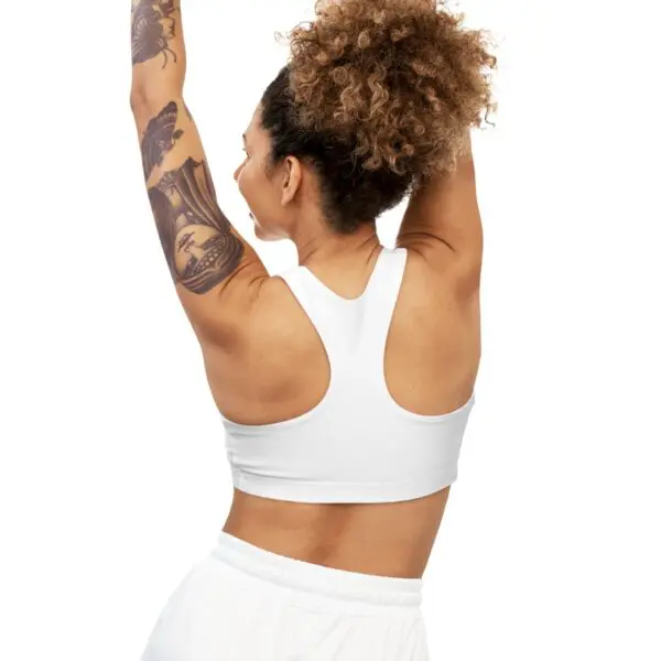 Woman with tattoos stretching in white outfit.