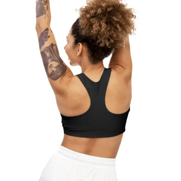 Woman with tattoos wearing a black sports bra.