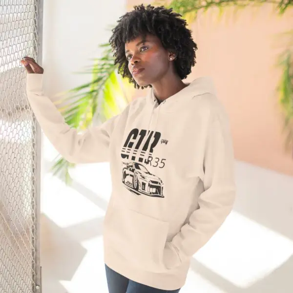 Woman in hoodie standing by a fence.