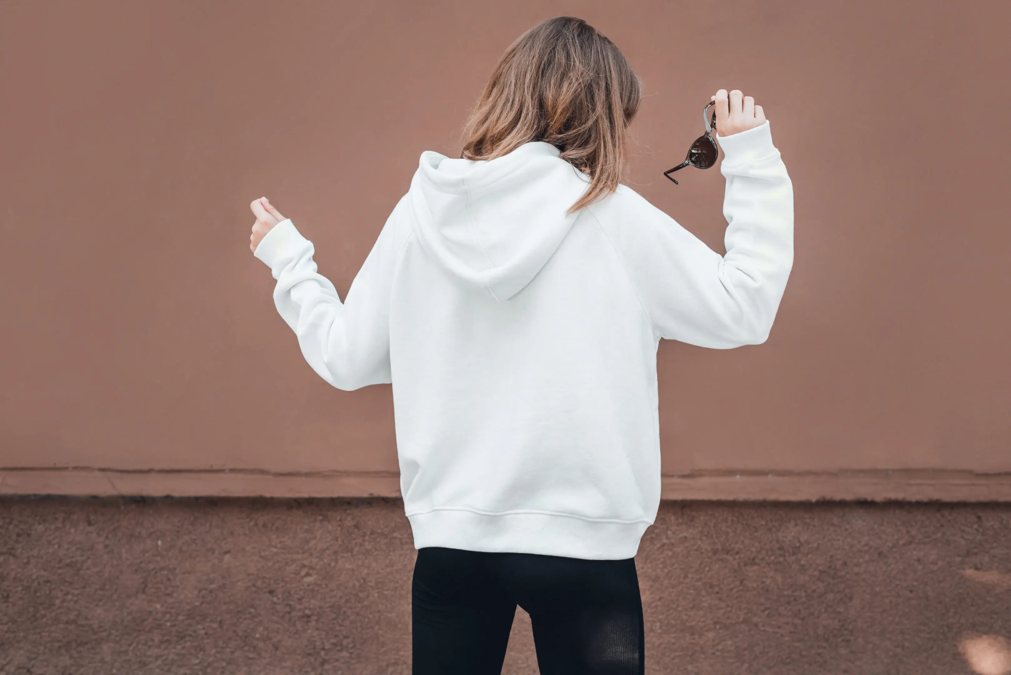 White hoodie on a young woman, mockup. Person in white hoodie holding sunglasses.